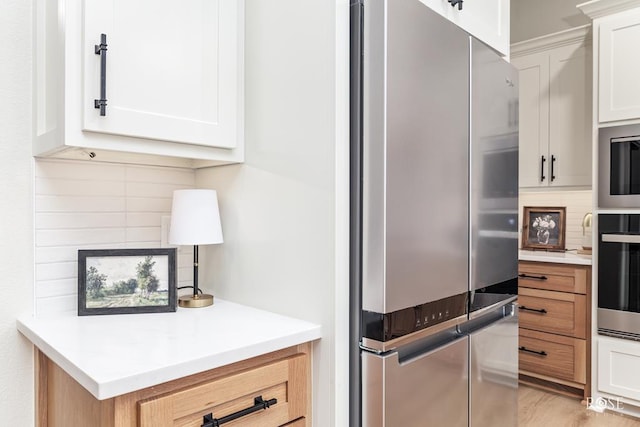 kitchen featuring light countertops, tasteful backsplash, stainless steel appliances, and white cabinetry