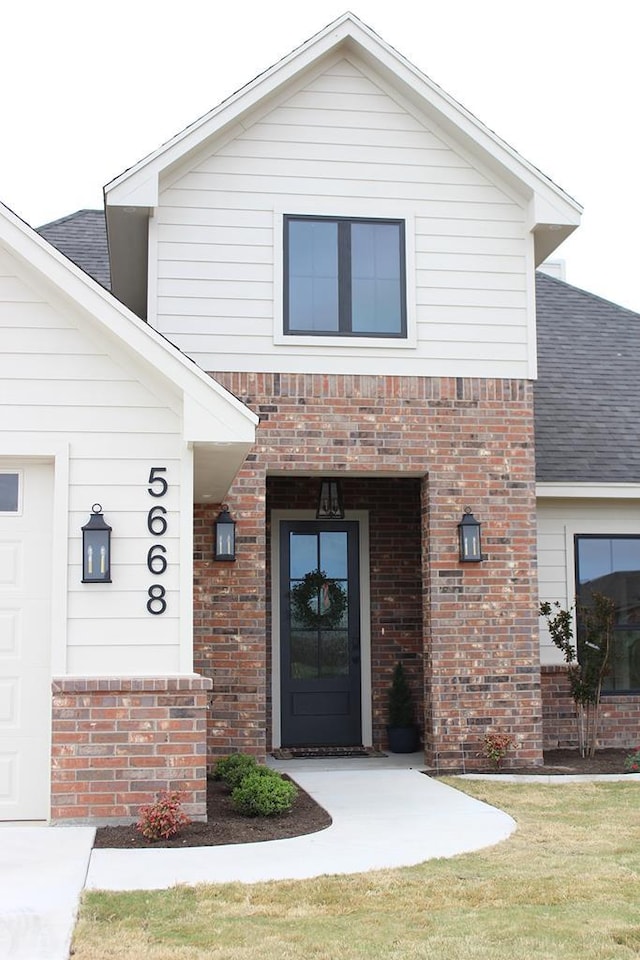 entrance to property with brick siding and a shingled roof