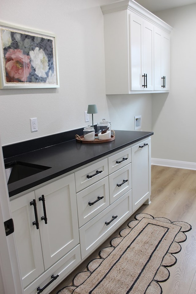 kitchen featuring light wood-style floors, baseboards, white cabinets, and dark countertops