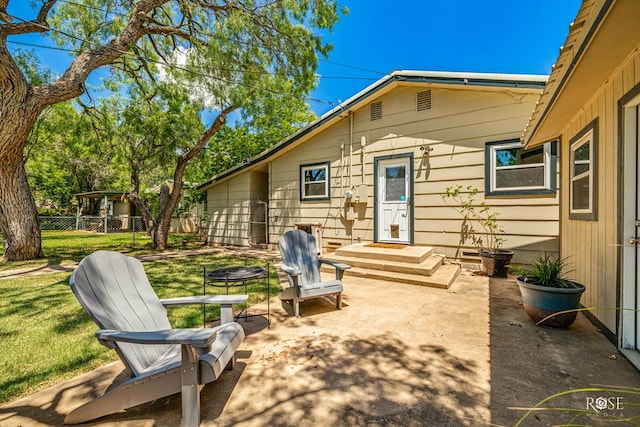 back of property with a fire pit, a yard, and a patio area