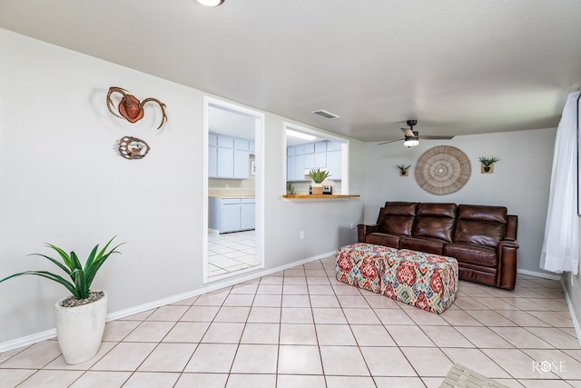 living room featuring ceiling fan, a textured ceiling, and light tile patterned floors