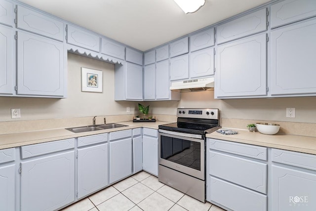 kitchen with light tile patterned flooring, sink, stainless steel range with electric cooktop, and white cabinets