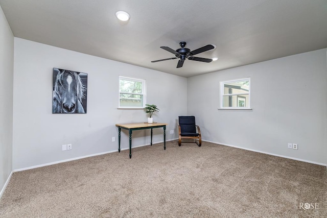 living area featuring carpet and ceiling fan