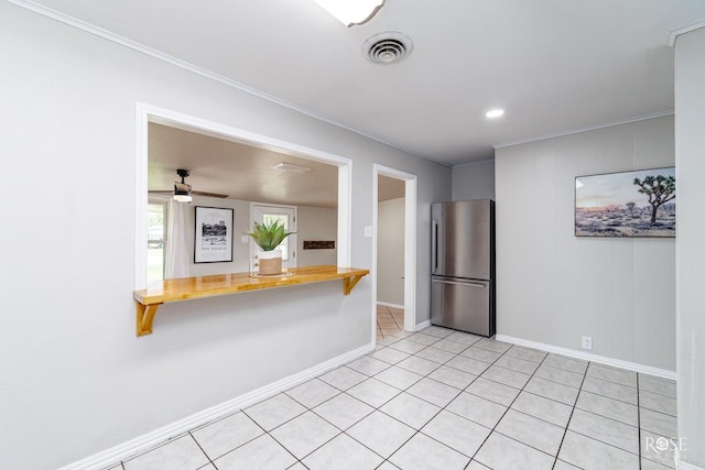 kitchen featuring butcher block countertops, ornamental molding, light tile patterned floors, and stainless steel refrigerator