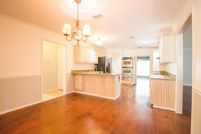 kitchen featuring decorative light fixtures, light hardwood / wood-style floors, kitchen peninsula, stainless steel appliances, and an inviting chandelier