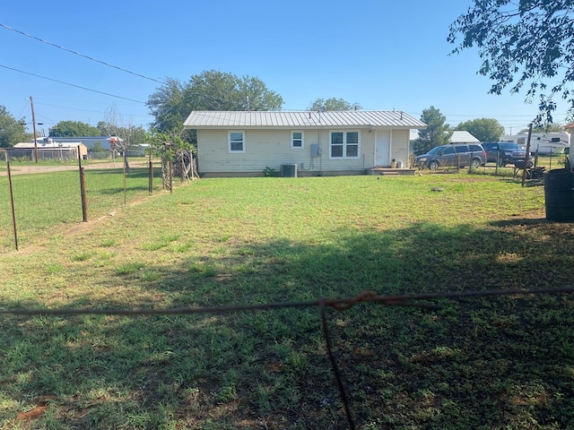 back of house with central AC unit and a lawn