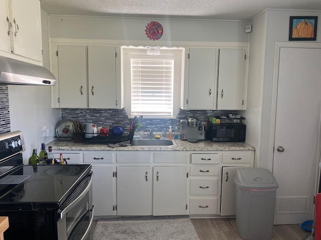 kitchen featuring range with two ovens, white cabinetry, sink, and decorative backsplash