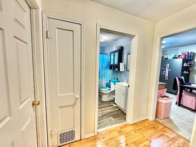 hallway featuring sink, a textured ceiling, and light wood-type flooring