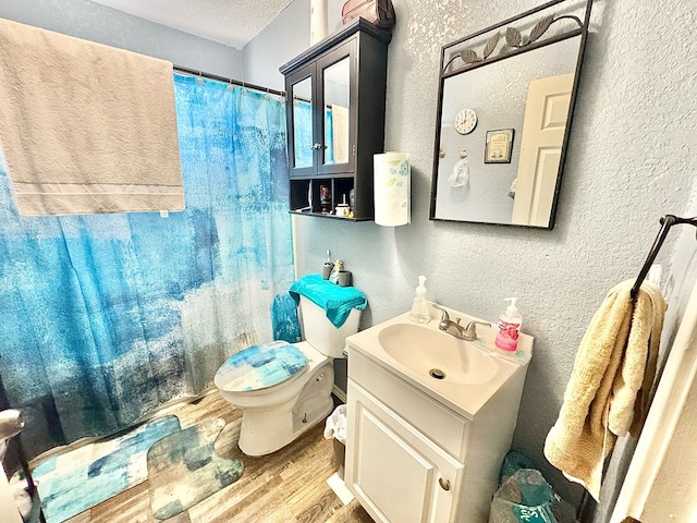 bathroom featuring hardwood / wood-style flooring, vanity, a textured ceiling, and toilet