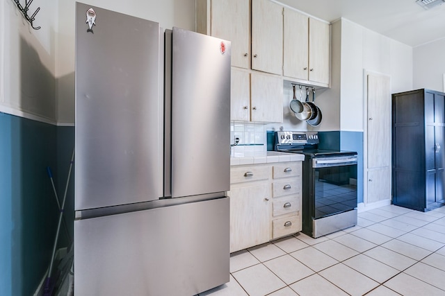 6376 Fm 380, San Angelo, TX 76905 - kitchen with appliances with stainless steel finishes, tile counters, light tile patterned floors, and tasteful backsplash