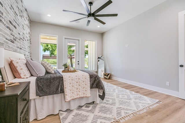 bedroom featuring ceiling fan, brick wall, light hardwood / wood-style flooring, and access to outside