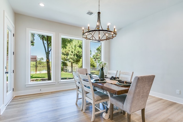 dining space featuring a healthy amount of sunlight, an inviting chandelier, and light hardwood / wood-style floors