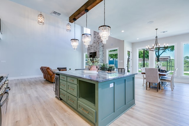 kitchen with pendant lighting, dark stone countertops, a center island, an inviting chandelier, and light hardwood / wood-style flooring