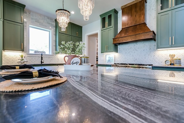 kitchen featuring custom exhaust hood, green cabinetry, decorative light fixtures, a chandelier, and dark stone counters