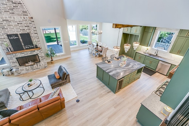 living room featuring a brick fireplace, sink, an inviting chandelier, and light hardwood / wood-style flooring