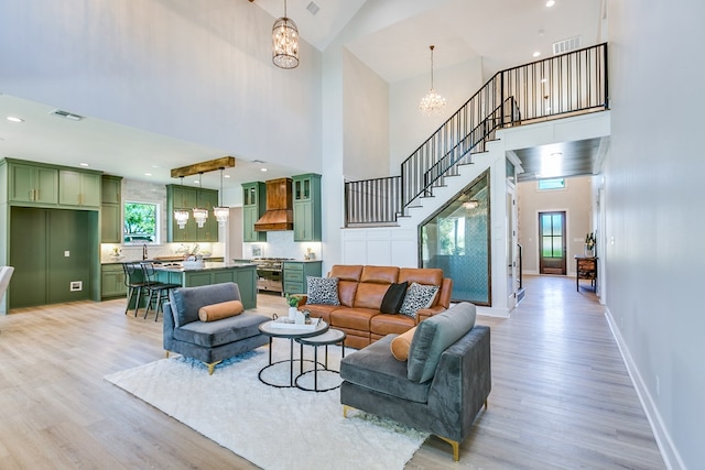 living room with a high ceiling, a chandelier, and light hardwood / wood-style floors