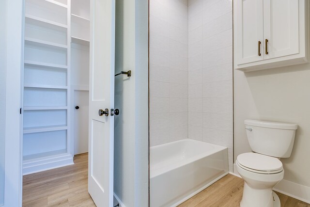 bathroom featuring hardwood / wood-style flooring, shower / tub combination, and toilet