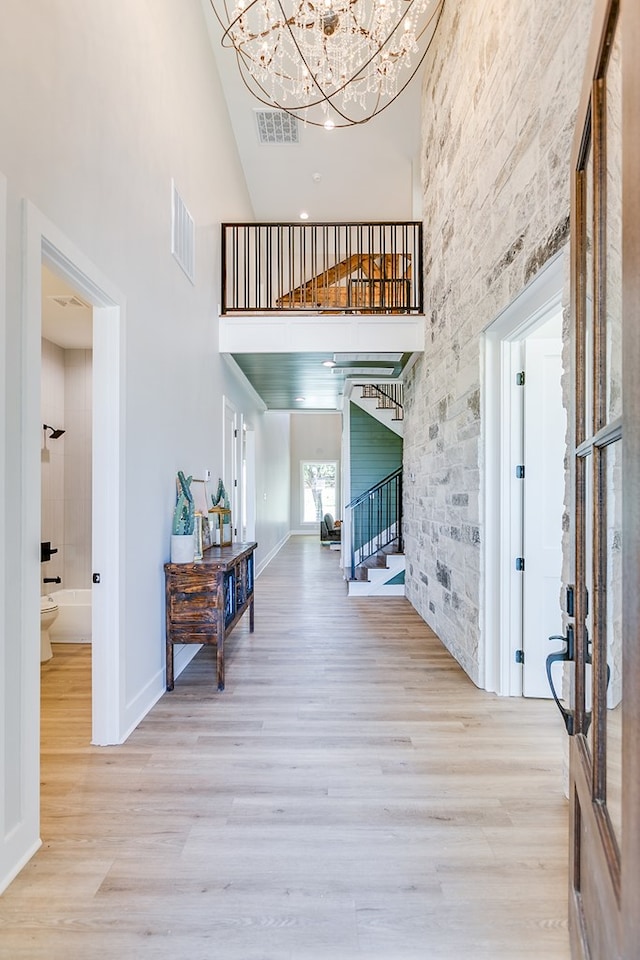 foyer featuring an inviting chandelier, a towering ceiling, and light hardwood / wood-style floors