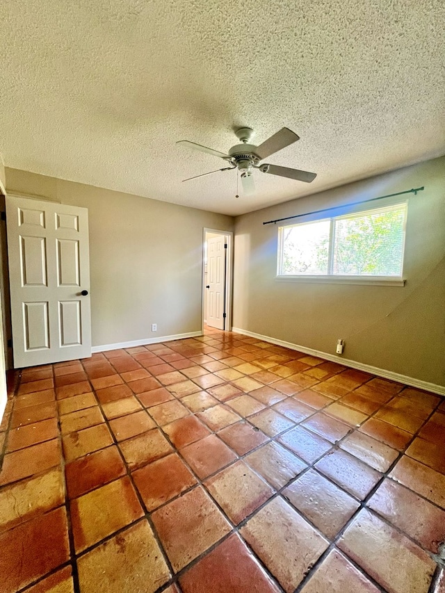 1013 Wynne Ave, San Angelo, TX 76905 - spare room with a ceiling fan, a textured ceiling, baseboards, and tile patterned floors