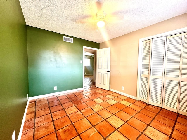 1013 Wynne Ave, San Angelo, TX 76905 - unfurnished bedroom with a textured ceiling, a closet, baseboards, a ceiling fan, and light tile patterned flooring