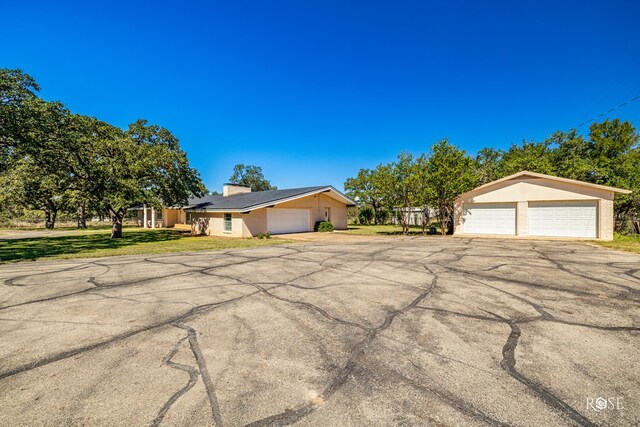 1124 W 6th St, Brady, TX 76825 - view of front of home with a front lawn, a chimney, stucco siding, and a garage