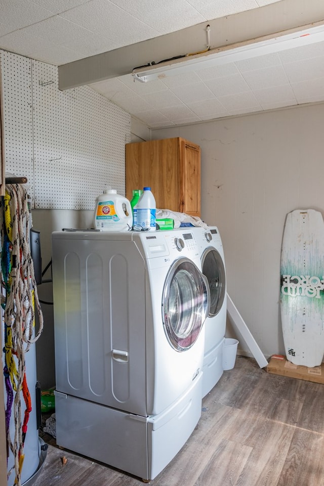 washroom with cabinets, wood-type flooring, and separate washer and dryer