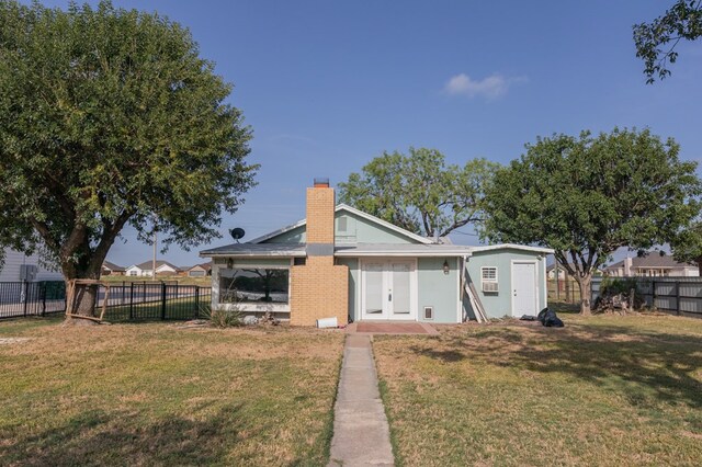 rear view of house with french doors and a lawn