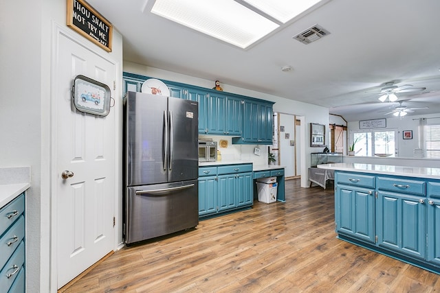 6038 Winners Cir, San Angelo, TX 76904 - kitchen featuring freestanding refrigerator, blue cabinets, light countertops, ceiling fan, and light wood-style floors