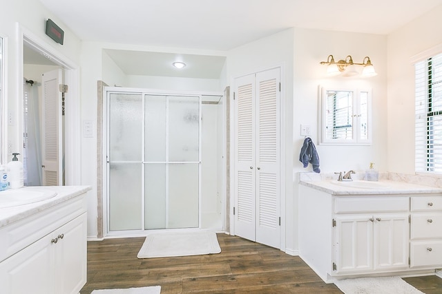 6038 Winners Cir, San Angelo, TX 76904 - bathroom with a closet, two vanities, a shower stall, and wood finished floors