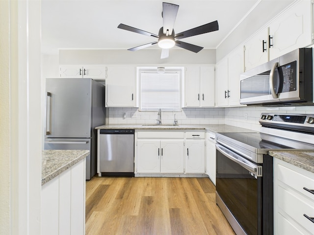 1203 Gordon Blvd, San Angelo, TX 76905 - kitchen with stainless steel appliances, a sink, white cabinetry, light wood-style floors, and crown molding