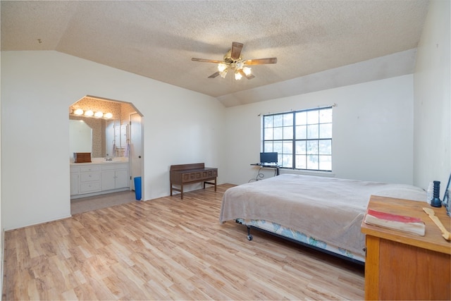 bedroom featuring vaulted ceiling, connected bathroom, ceiling fan, light hardwood / wood-style floors, and a textured ceiling