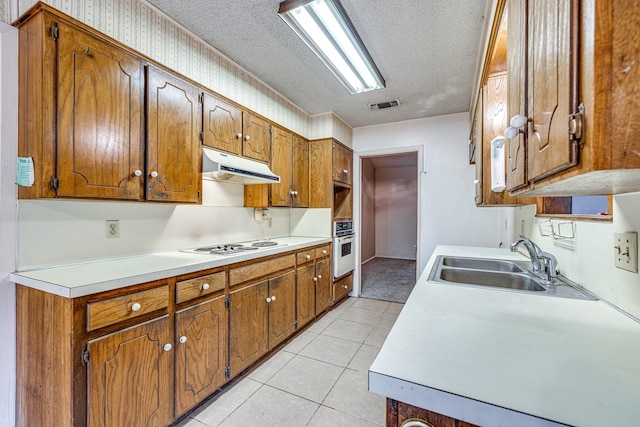 kitchen featuring light tile patterned flooring, white appliances, sink, and a textured ceiling