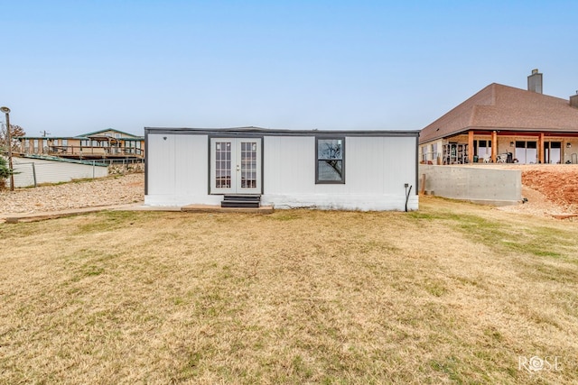 back of property with a lawn and french doors