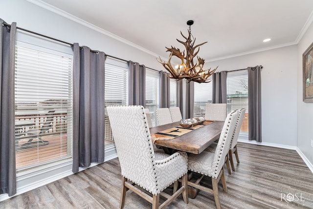 dining area featuring a healthy amount of sunlight, wood-type flooring, ornamental molding, and a chandelier