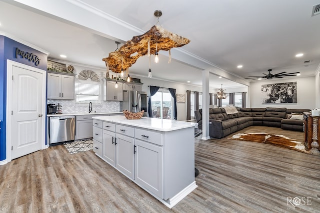 kitchen with gray cabinets, stainless steel appliances, a center island, decorative backsplash, and light wood-type flooring