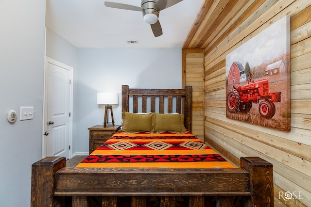 bedroom featuring carpet floors, ceiling fan, and wood walls