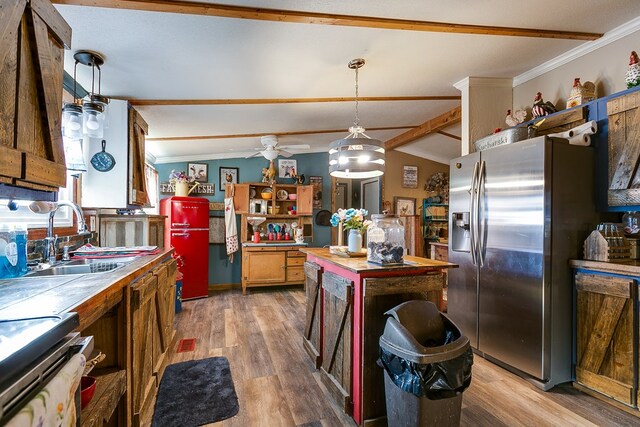 kitchen featuring vaulted ceiling, hardwood / wood-style floors, decorative light fixtures, sink, and stainless steel fridge with ice dispenser