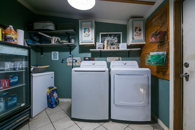 clothes washing area with crown molding, washer and dryer, and light tile patterned flooring