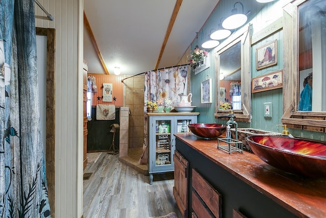 bathroom featuring vanity, wooden walls, curtained shower, and hardwood / wood-style floors