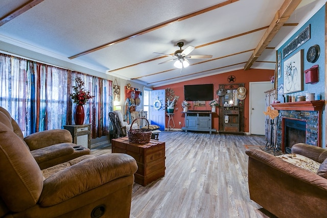 living room with vaulted ceiling with beams, a textured ceiling, light hardwood / wood-style flooring, ceiling fan, and a fireplace