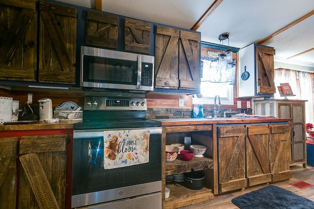 kitchen with appliances with stainless steel finishes, light hardwood / wood-style floors, sink, and a textured ceiling