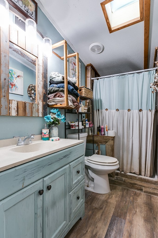 bathroom with a skylight, wood-type flooring, vanity, toilet, and crown molding