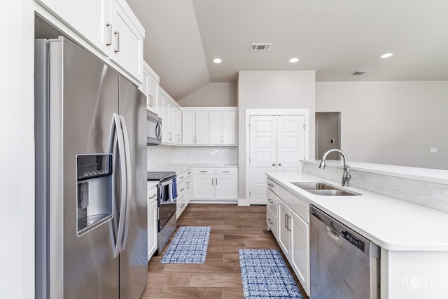 kitchen featuring lofted ceiling, sink, white cabinetry, stainless steel appliances, and decorative backsplash