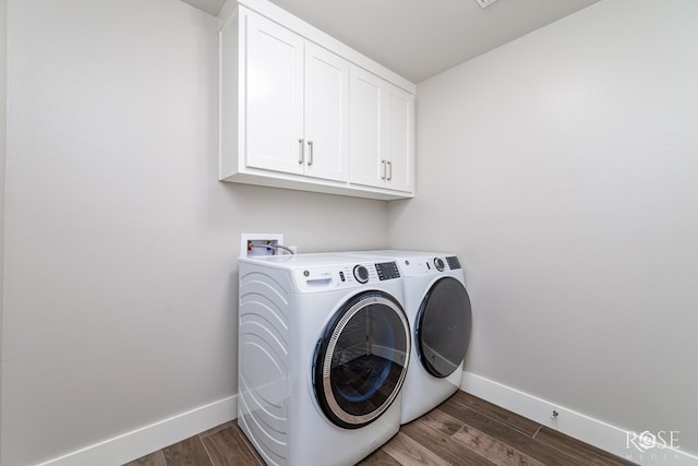 laundry area with dark wood-type flooring, cabinets, and washing machine and clothes dryer