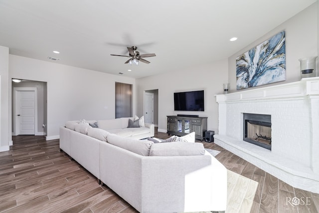 living room featuring a brick fireplace and ceiling fan