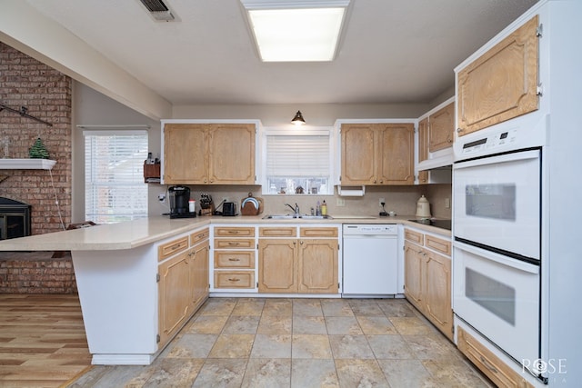 kitchen featuring sink, light brown cabinetry, white appliances, and kitchen peninsula