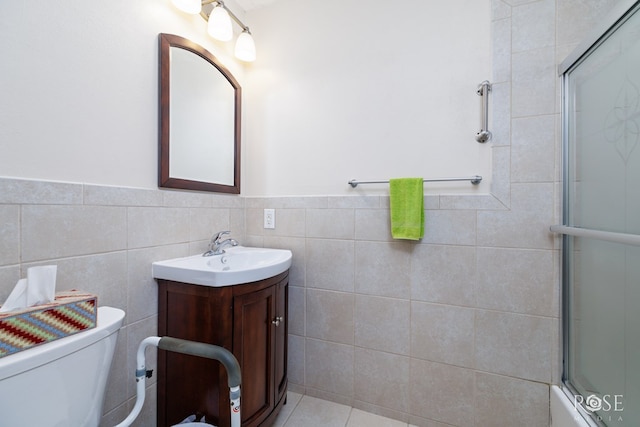 full bathroom with vanity, combined bath / shower with glass door, tile walls, and toilet