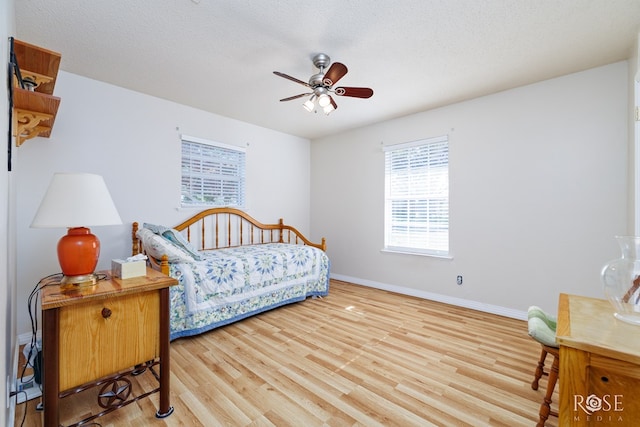 bedroom with ceiling fan, light hardwood / wood-style floors, and a textured ceiling