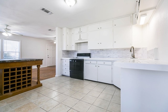 1221 Howard Ave, San Angelo, TX 76901 - kitchen with black electric range oven, a ceiling fan, and backsplash