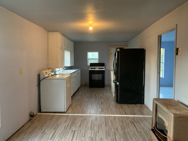 620 W 19th St, San Angelo, TX 76903 - kitchen with gas stove, washer / clothes dryer, freestanding refrigerator, light wood-style floors, and white cabinetry